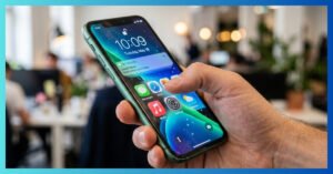 Fotografia em close-up de um iPhone 11 verde rodando a interface futurista do iOS 26 Liquid Glass em 2026.
